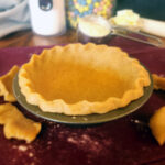 Pie crust in a pie tin with ingredients in the background