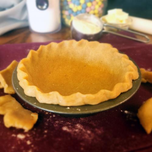 Pie crust in a pie tin with ingredients in the background