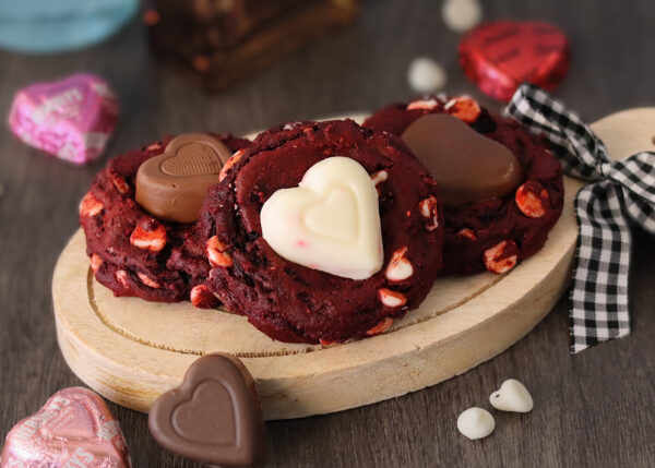 An assortment of red velvet sweetheart cookies on a small wooden board.