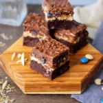 Almond Coconut Crunch Brownies stacked on a wooden board
