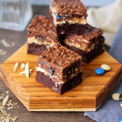 Almond Coconut Crunch Brownies stacked on a wooden board