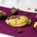 PBC Montage Cookie close up on a purple napkin with ingredients scattered in the background.