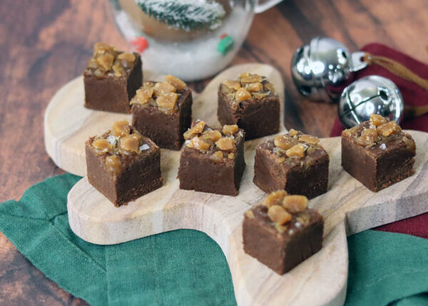 Salted caramel toffee fudge arranged on a gingerbread man shaped serving tray with Christmas holiday decor.