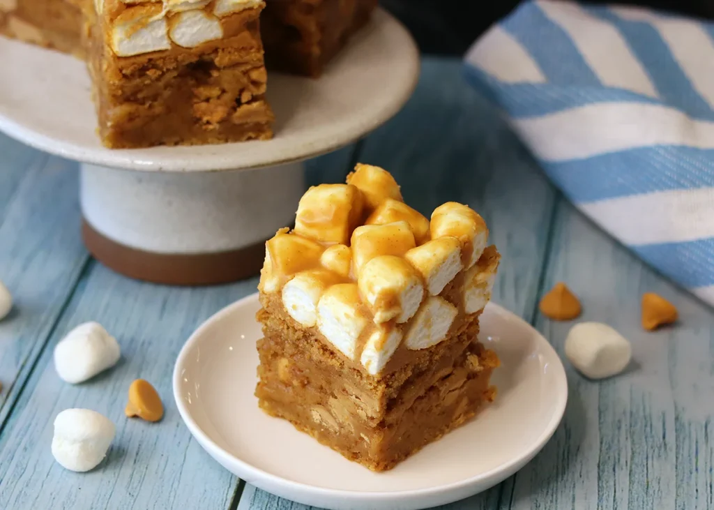 A butterbeer blondie on a small plate showing the fudgie blondie layer and marshmallow "foam" top.