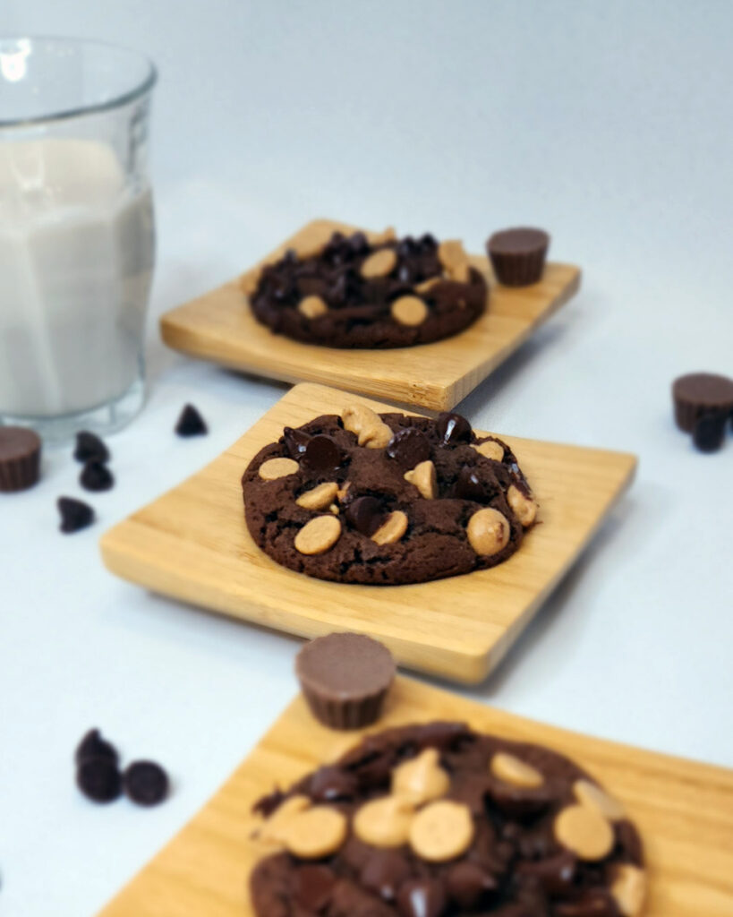 Double Chocolate Chip Cookies on small wooden plates with a glass of milk.
