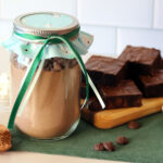 A jar of DIY brownie mix with assorted ingredients and a platter of baked brownies.