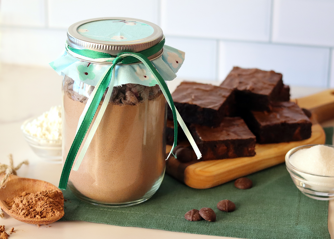 A jar of DIY brownie mix with assorted ingredients and a platter of baked brownies.