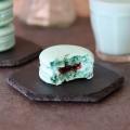 A Mandalorian Macaron on a black hexagonal plate with a bite exposing the raspberry and buttercream fillings.
