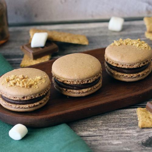 S'mores Macarons on an oblong wooden plate