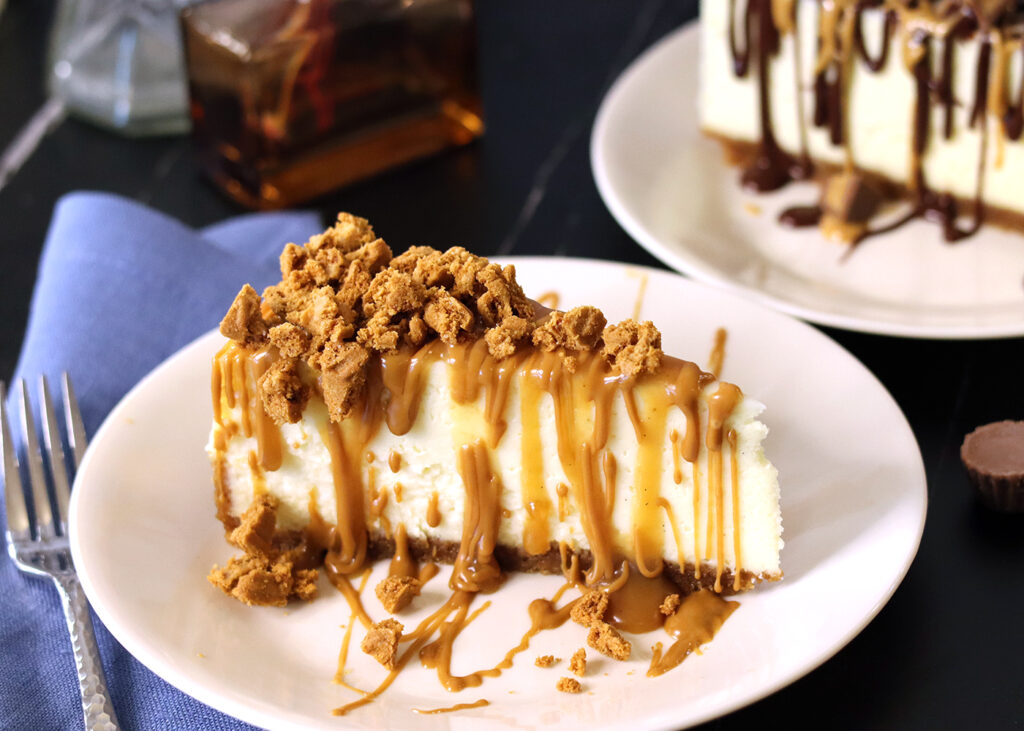 New York Cheesecake slice topped with a drizzle of melted cookie butter and crumbled Biscoff cookies