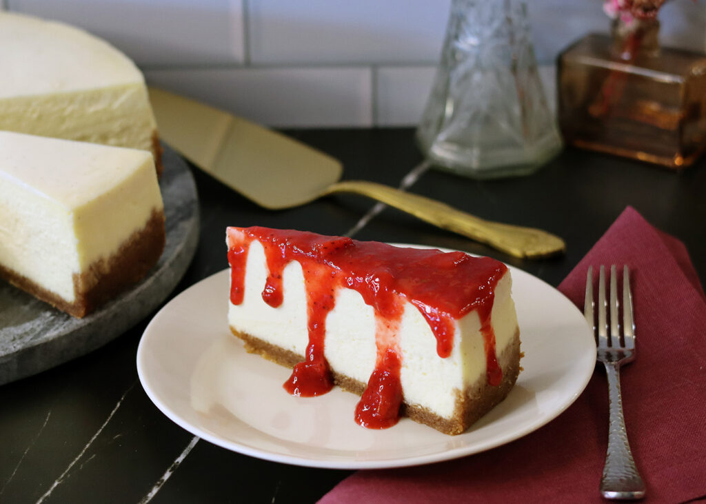 New York Cheesecake slice topped with fresh strawberry sauce