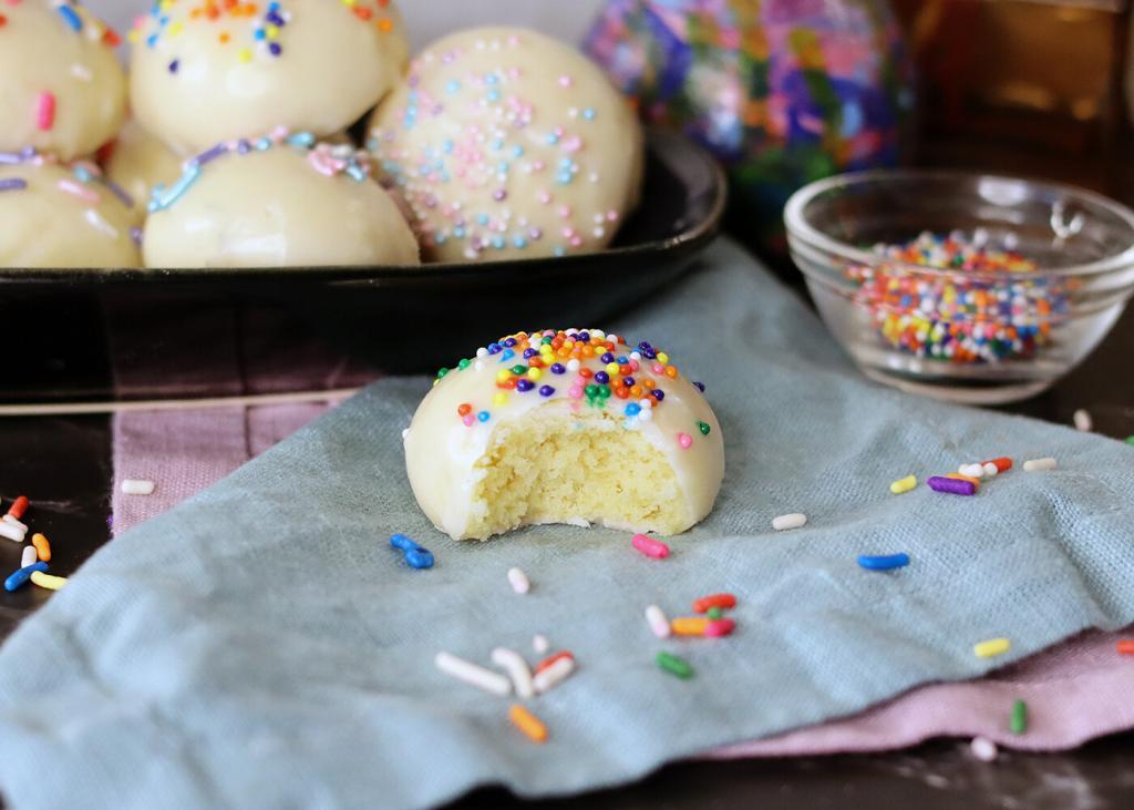 Italian Sprinkle Cookies on a serving platter, one with a bite missing.