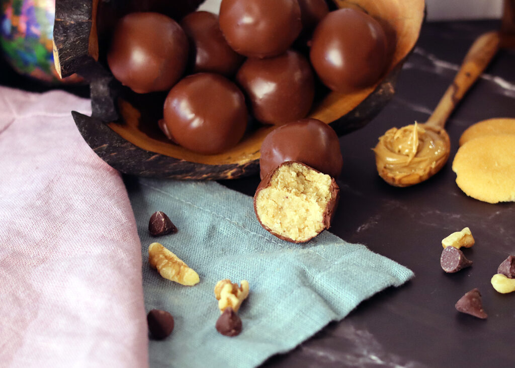 Peanut Butter Balls piled on a serving tray, with one broken open