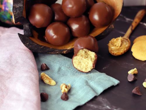 Peanut Butter Balls piled on a serving tray, with one broken open