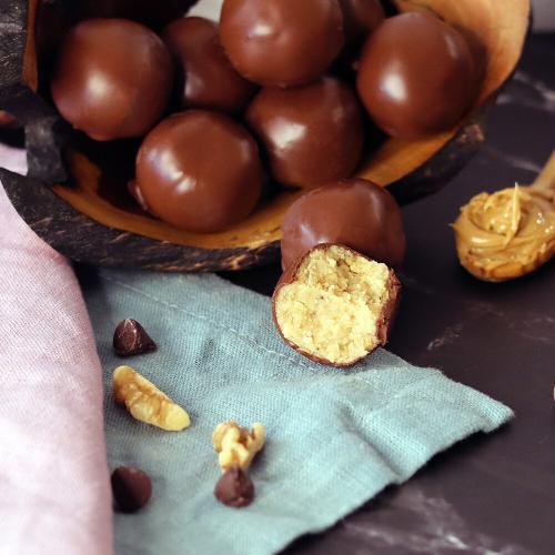 Peanut Butter Balls piled on a serving tray, with one broken open