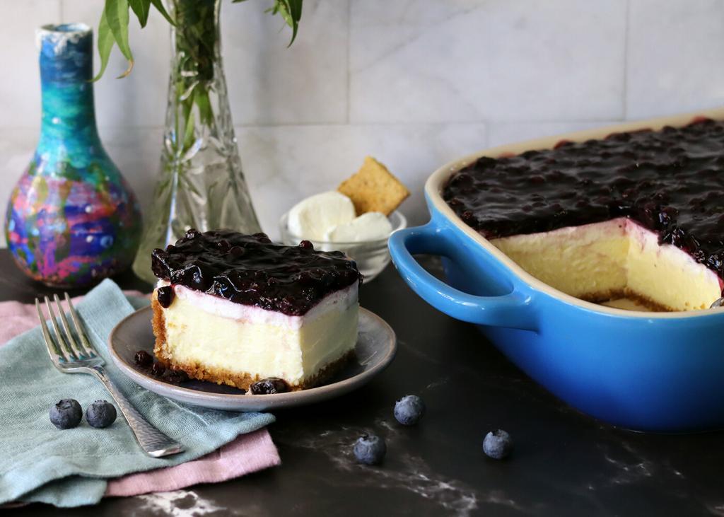 Mom's Cheesecake slice on a plate next to the pan of cheesecake