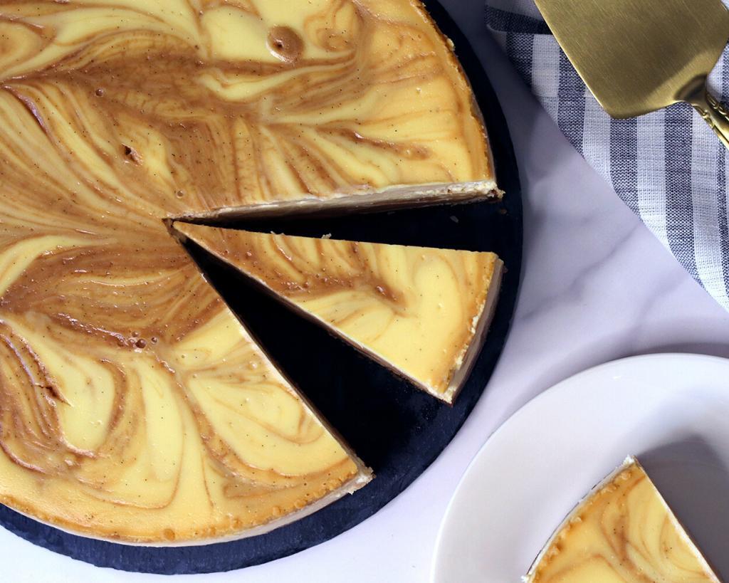 Vanilla Bean Caramel Goat Cheese Cheesecake top down view with a slice separated from the whole cake