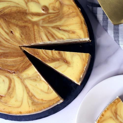 Vanilla Bean Caramel Goat Cheese Cheesecake top down view with a slice separated from the whole cake