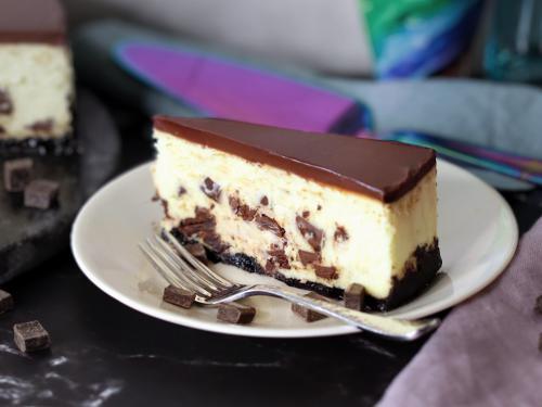 Chocolate Chunk Cheesecake slice on a white plate.