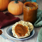 Pumpkin Butter spread on an English muffin with pumpkins in the background.