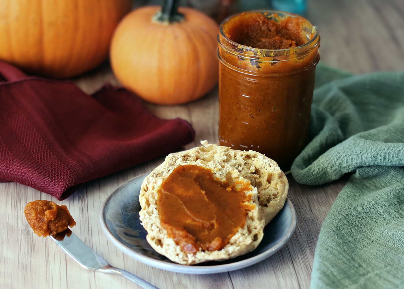 Pumpkin Butter spread on an English muffin with pumpkins in the background.