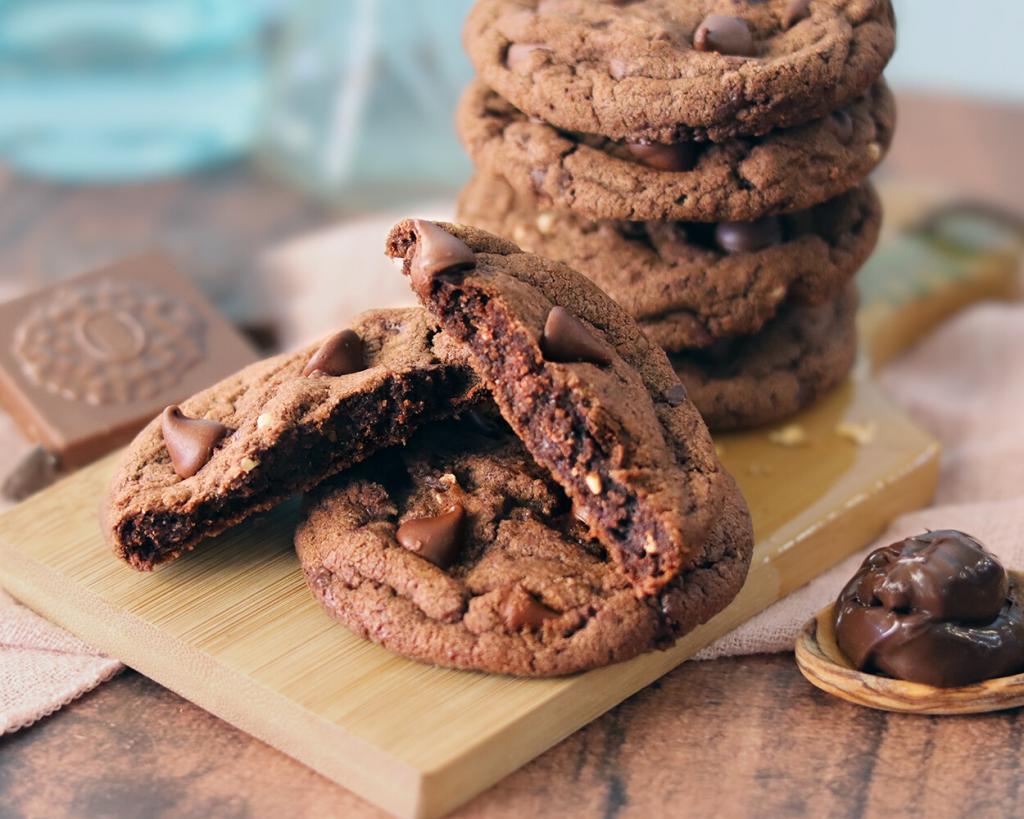 Ferrero Rocher Chocolate Chip Cookies stacked on a small board with one broken open to show the interior texture.