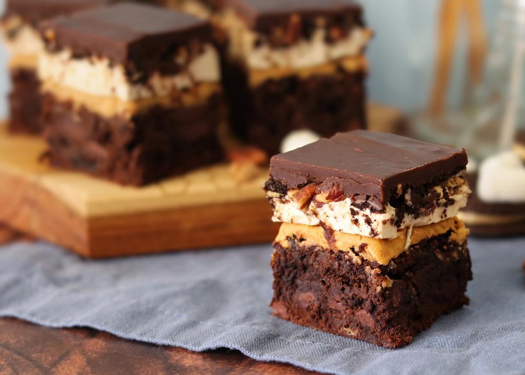Mississippi Mudpie Brownie on a blue napkin in front of a wooden platter of brownies.
