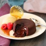 Molten Chocolate Cake broken open on a white plate with berries, cream and caramel garnish.