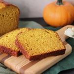 Mom's Pumpkin Bread sliced on a cutting board with a pumpkin in the background
