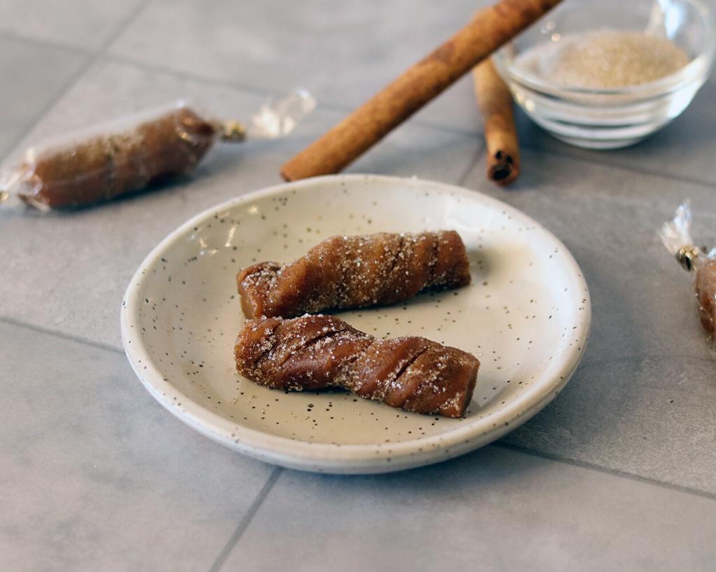 Churro Caramels on a small plate showing a spiral texture and cinnamon sugar coating.