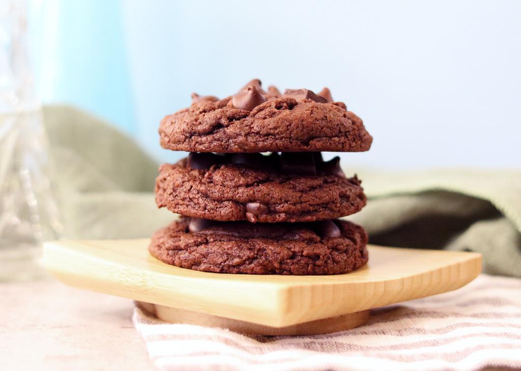 Side angle view of a stack of Double Chocolate Chip Sourdough Cookies on a small wooden board