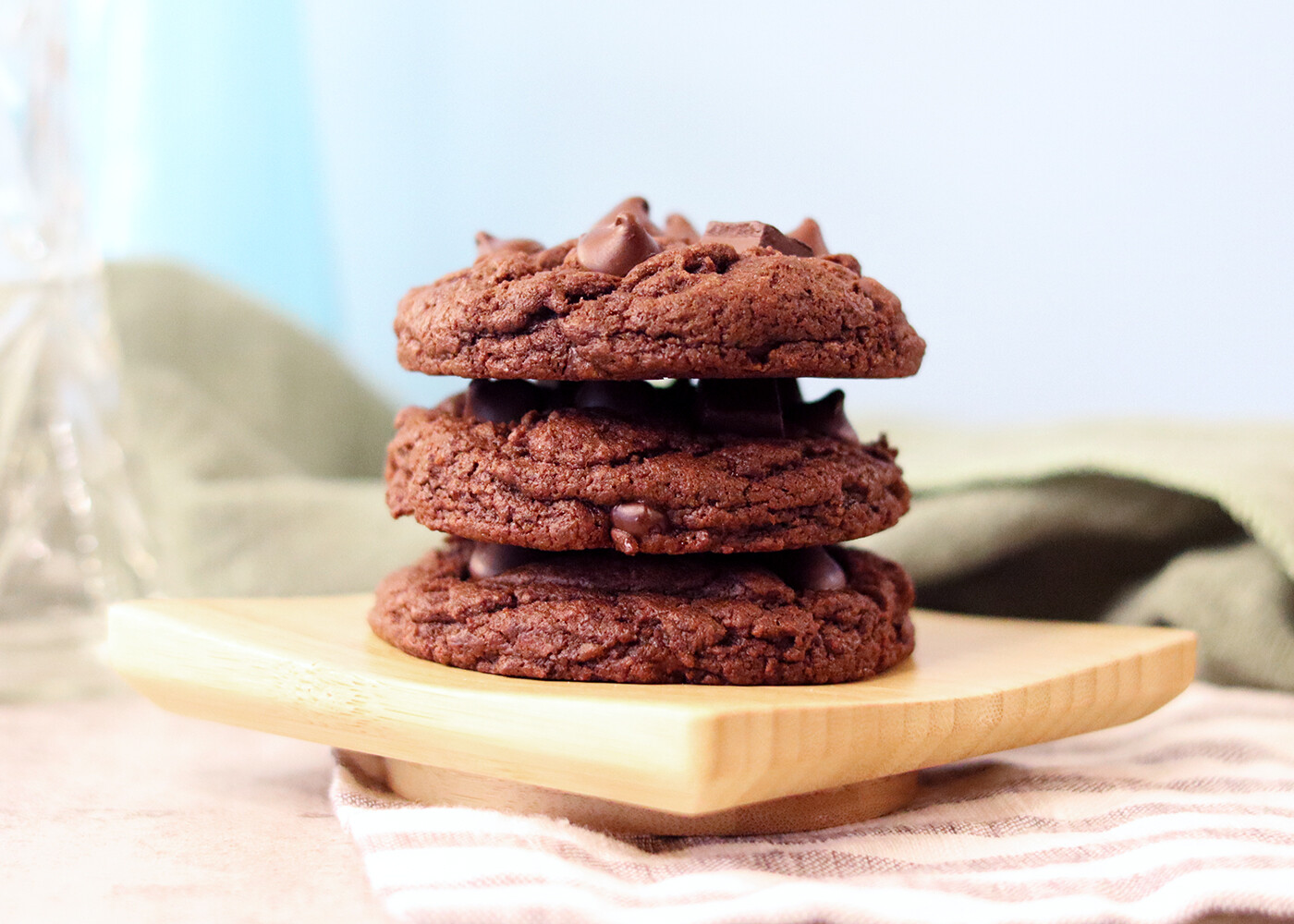 a stack of Double Chocolate Chip Sourdough Cookies on a small wooden dish.