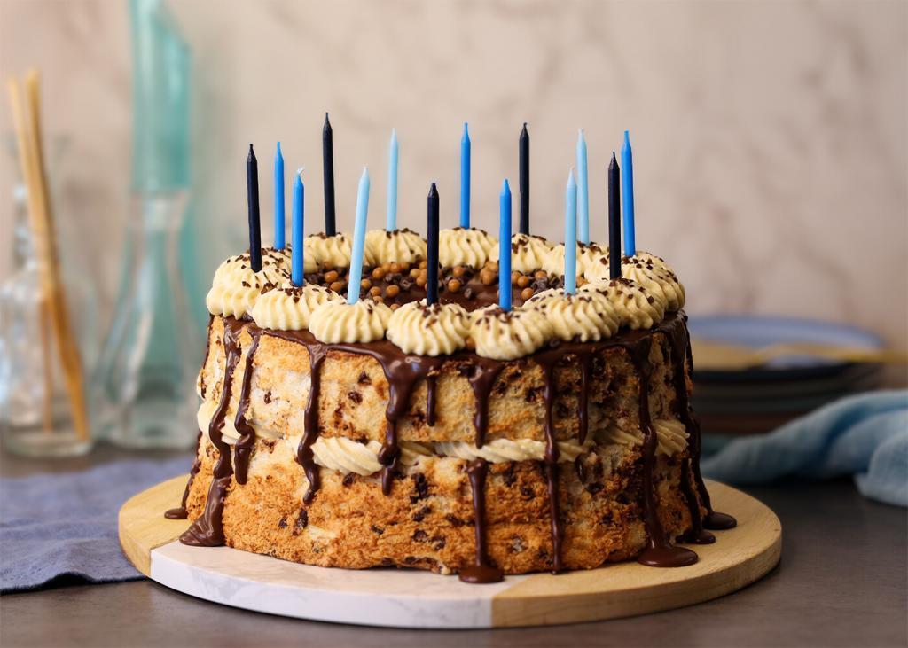 A whole Angel Food Cake dressed up for a birthday with cream, chocolate and candles.