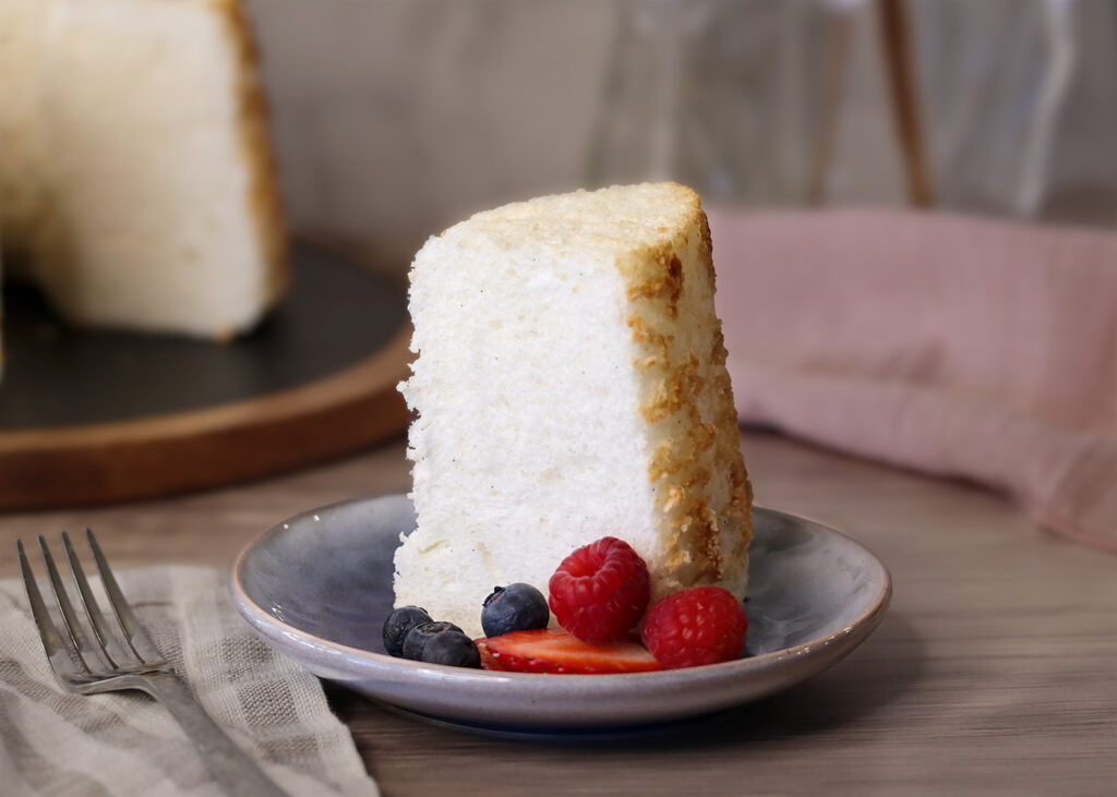 A slice of Angel Food Cake served plain with a few berries.