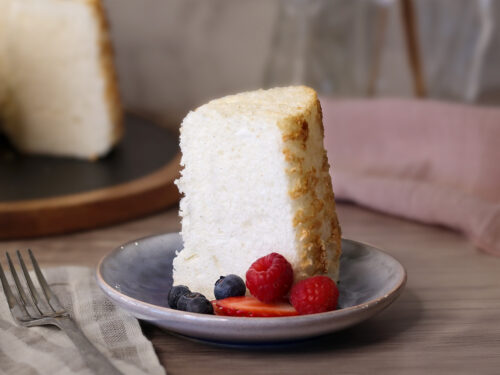A slice of Angel Food Cake served plain with a few berries.