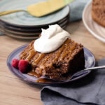 A slice of cocoa angel food cake with a drizzle of caramel and dollop of cream.