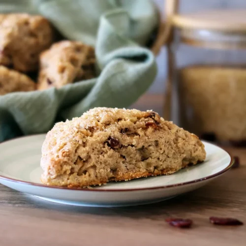 Cranberry Pear Scone on a small plate with a basket of scones in the background.
