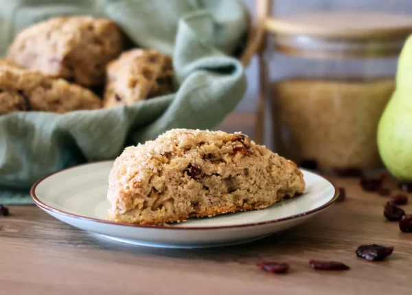 Cranberry Pear Scone on a small plate with a basket of scones in the background.