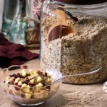 A jar of DIY 100cal Oatmeal Mix next to a prepared bowl of oatmeal.