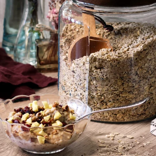 A jar of DIY 100cal Oatmeal Mix next to a prepared bowl of oatmeal.