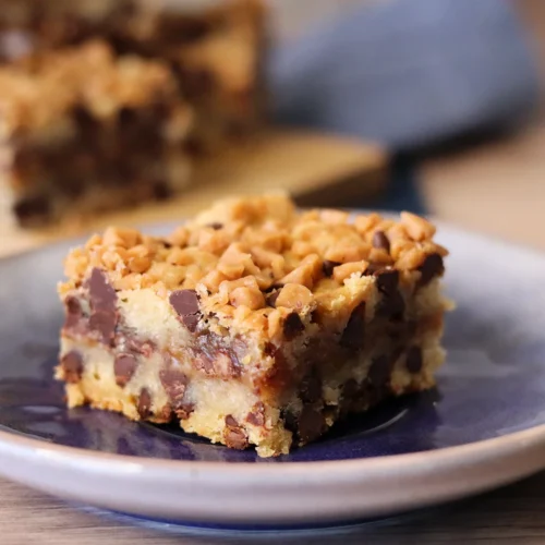 Chocolate Chip Toffee Bar close up on a small plate with clear layers, visible chocolate chips, and golden toffee on top.