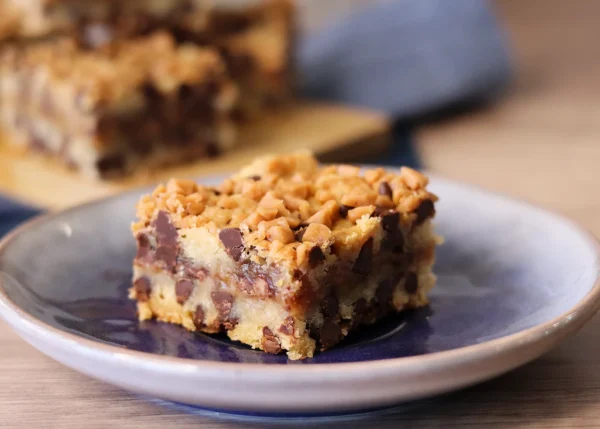 Chocolate Chip Toffee Bar close up on a small plate with clear layers, visible chocolate chips, and golden toffee on top.
