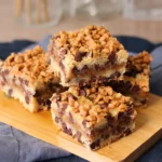 Chocolate Chip Toffee Bars stacked on a small cutting board showing the texture of the layers and toppings.