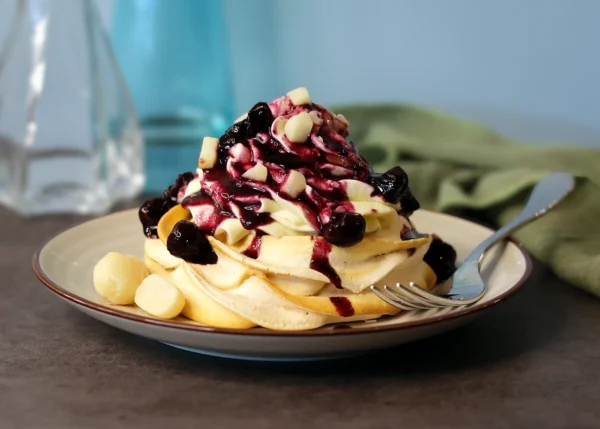 Mini Pavlova swirled with blonde chocolate and topped with cheesecake mousse, blueberry topping and chopped macadamia nuts.