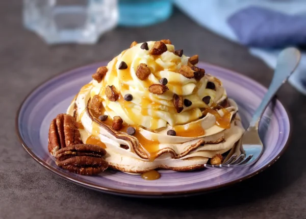 Mini Pavlova swirled with dark chocolate and served with cheesecake mousse, caramel, pecans and mini chocolate chips.