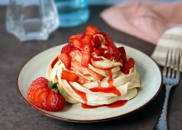 Mini Pavlova served with cheesecake mousse and macerated strawberries.