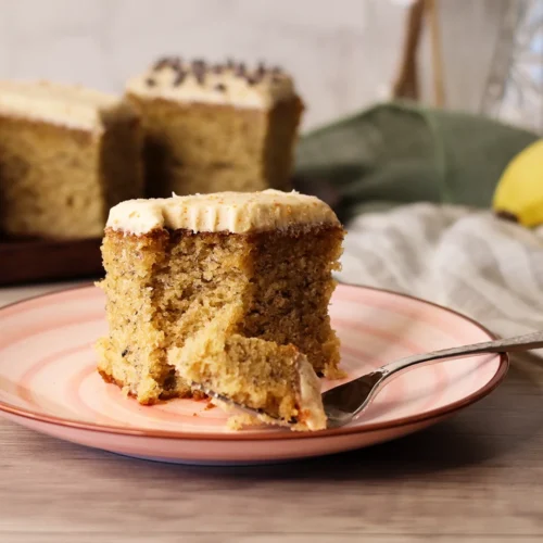 A piece of Brown Butter Banana Snack Cake with a bite missing showing the interior crumb texture.