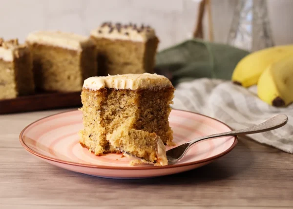A piece of Brown Butter Banana Snack Cake with a bite missing showing the interior crumb texture.