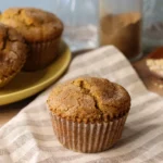 Chai Spiced Banana Muffin on a striped linen napkin with more muffins in the background.