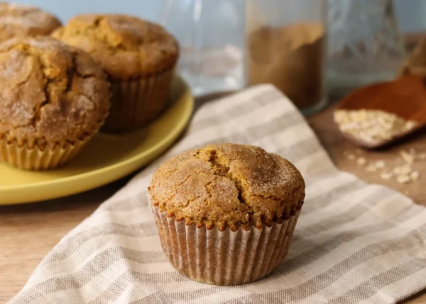 Chai Spiced Banana Muffin on a striped linen napkin with more muffins in the background.